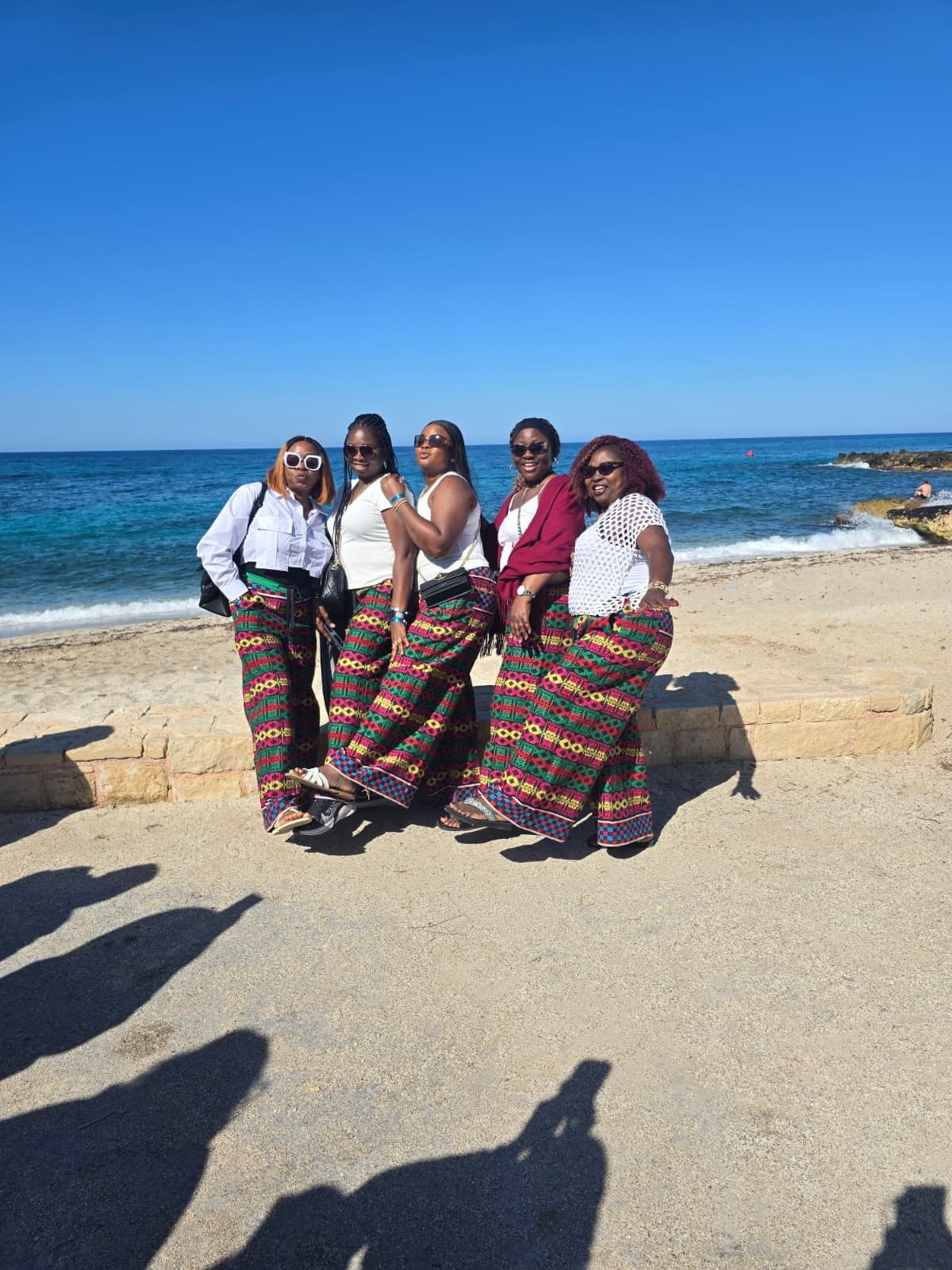 Five women in matching printed trousers on the beach