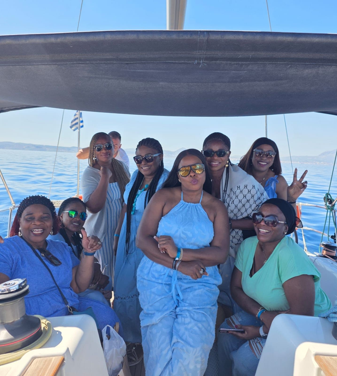 Eight women in shades of blue posing together on a sailing boat