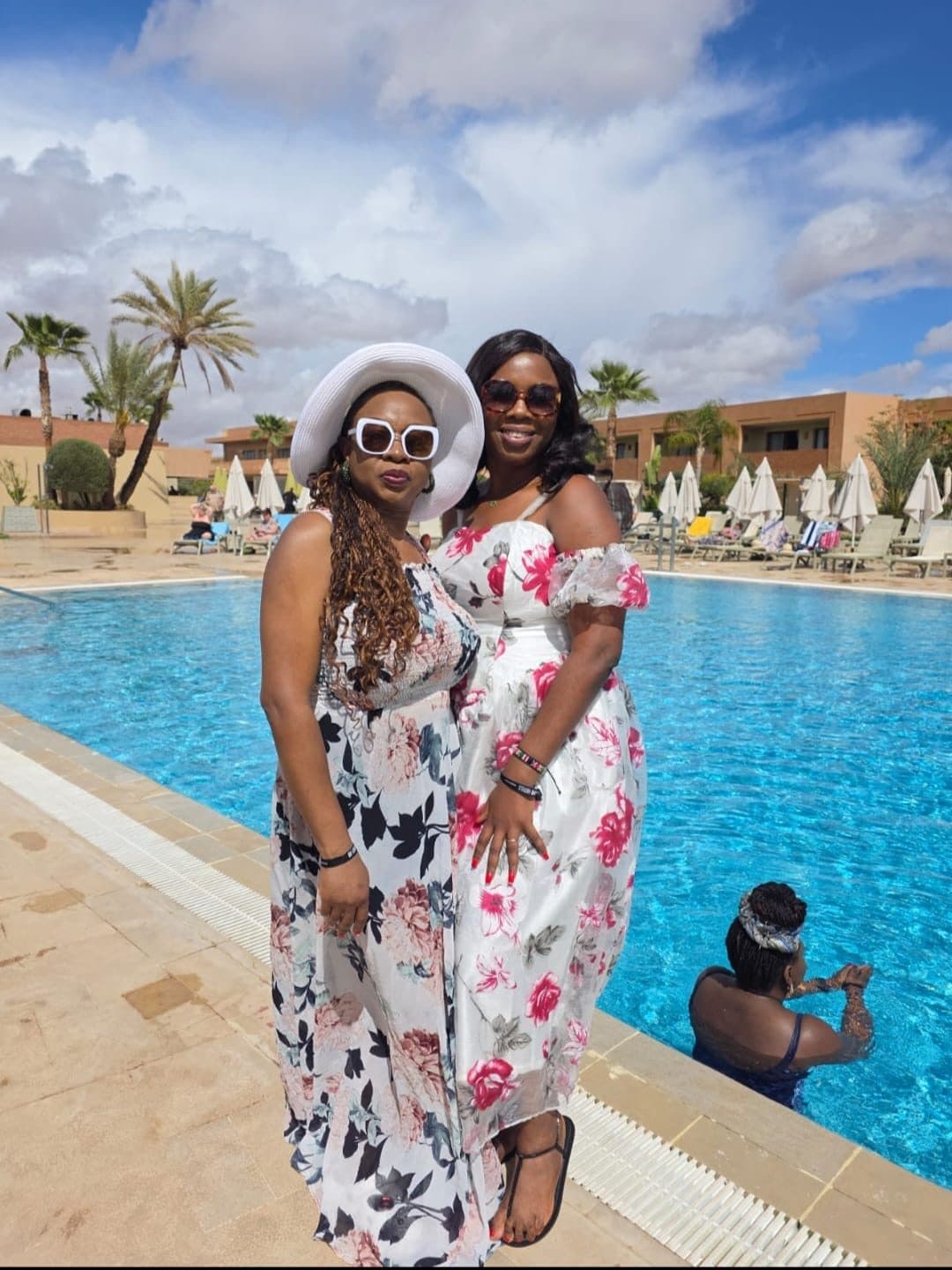 Dinma and Bokun by the pool in floral dresses