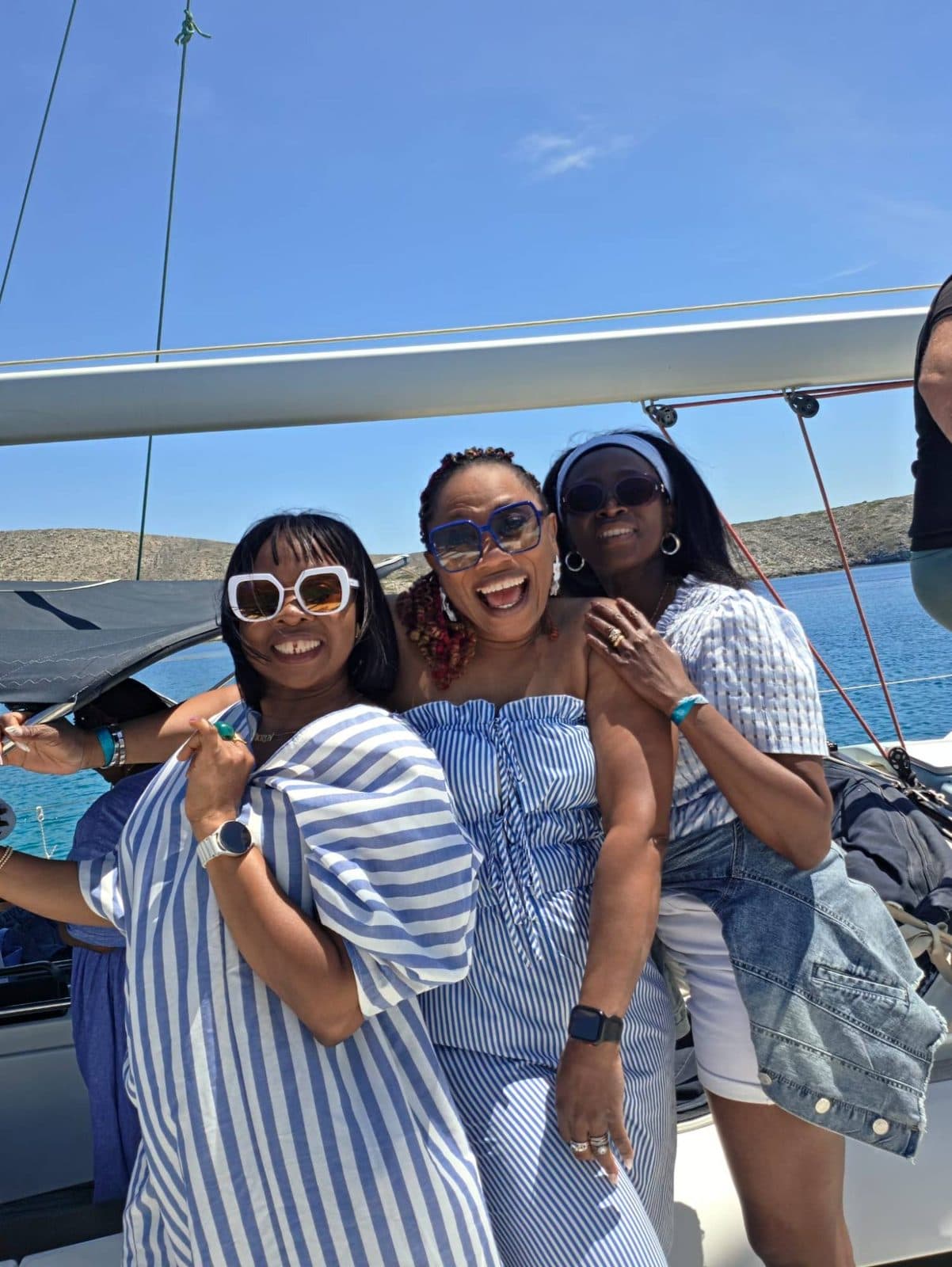 Three women in blue and white stripes laughing on a boat
