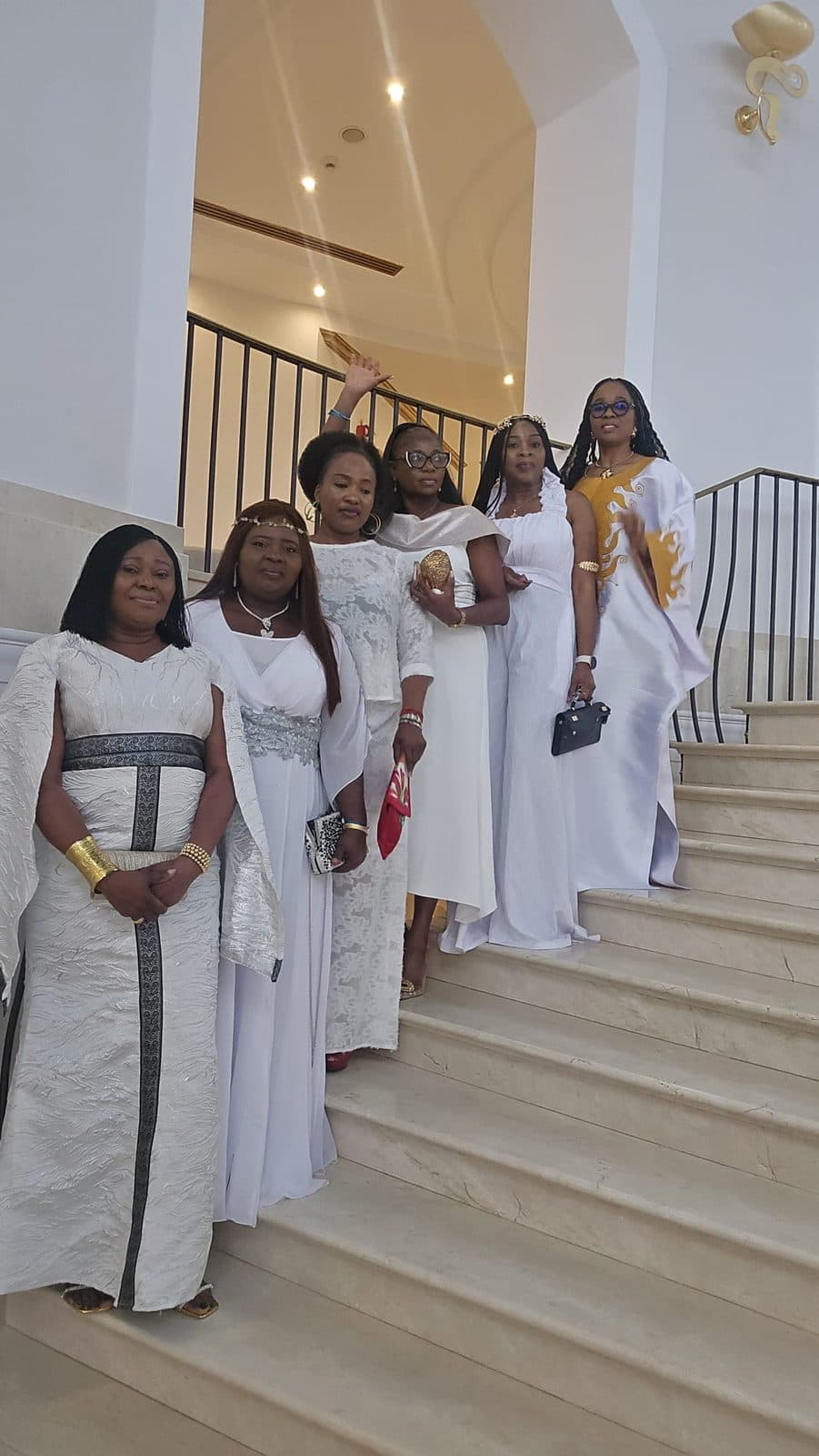 Women in white and gold outfits on a marble staircase