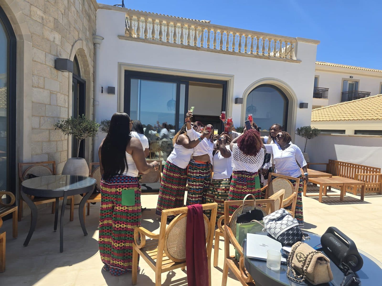 SHE-CATION 3.0 guests in matching printed trousers raising a toast on a sunny terrace